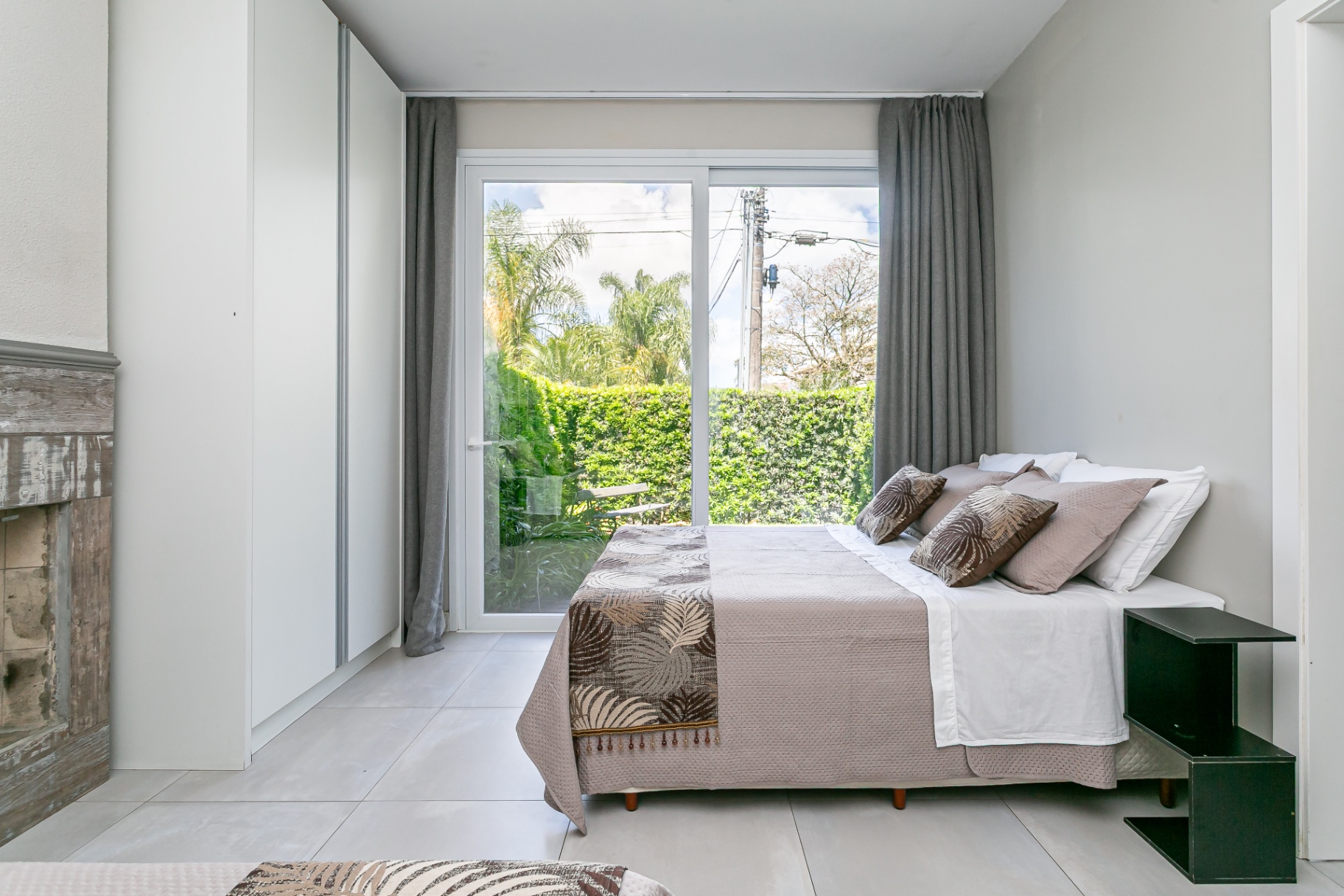 Quarto da Casa Noah com cama de casal e porta de vidro de correr para o jardim