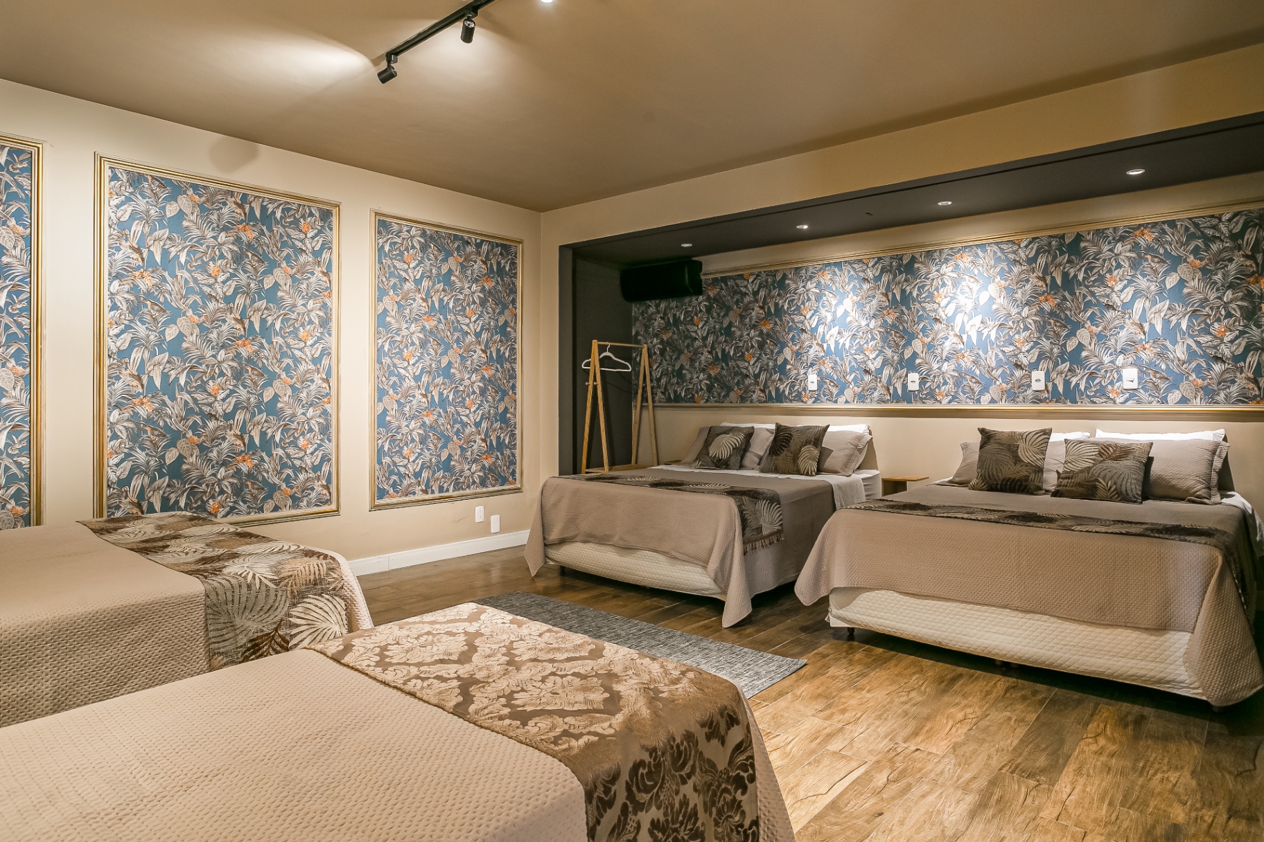 Quarto amplo da Casa Noah com quatro camas e papel de parede floral