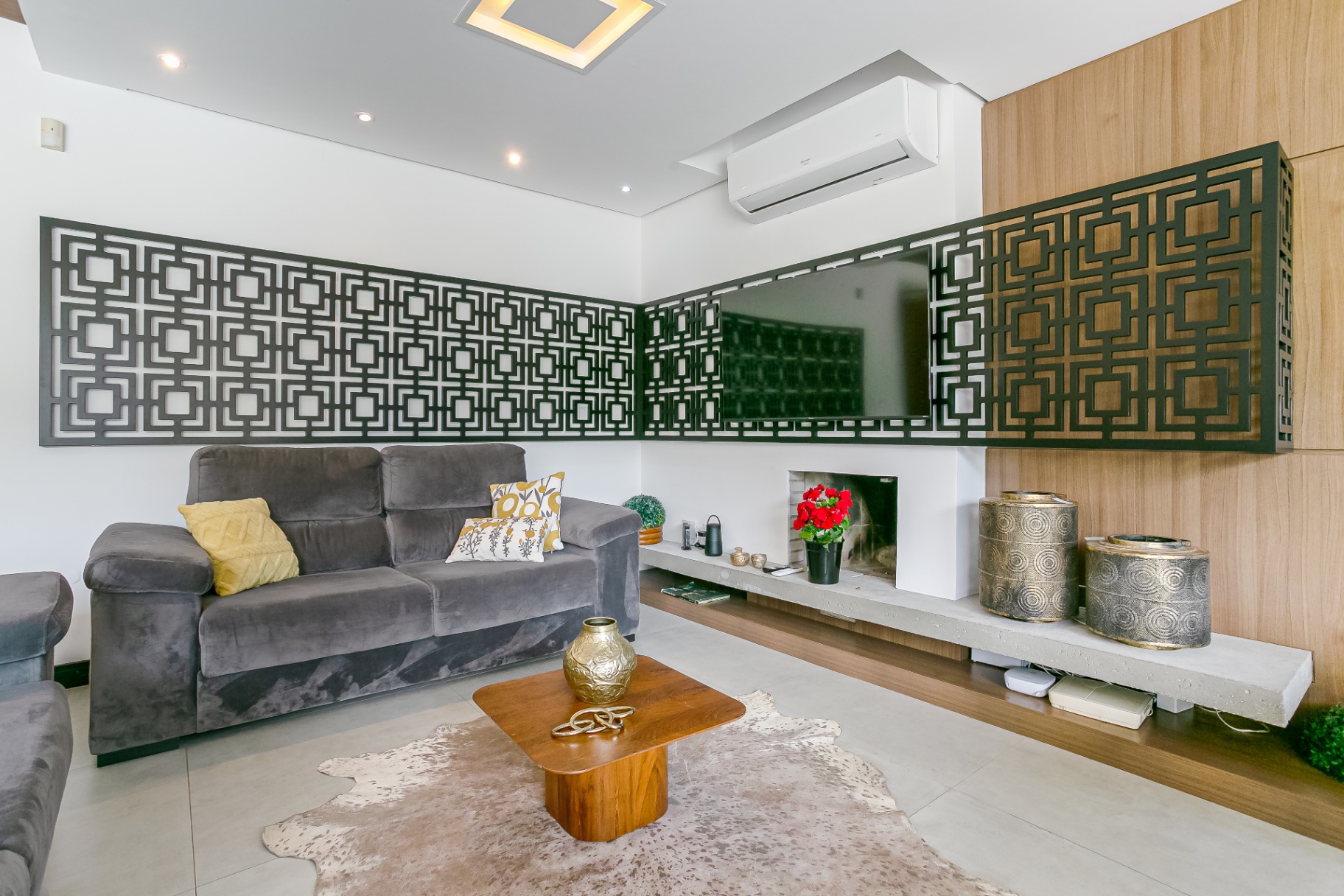Sala de estar da Casa Noah com painel geométrico e lareira minimalista