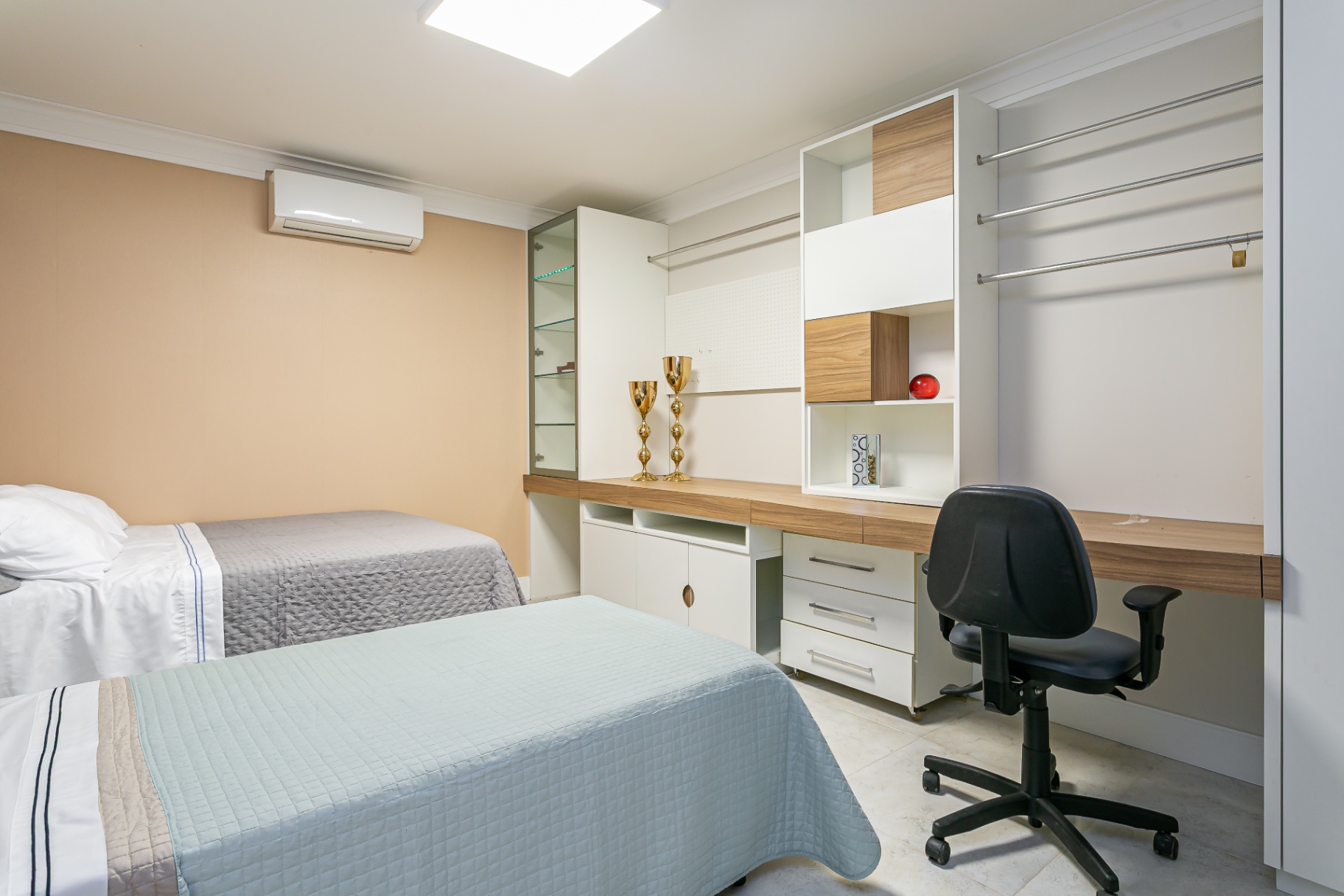 Quarto com duas camas e bancada de home office da Casa Nevi