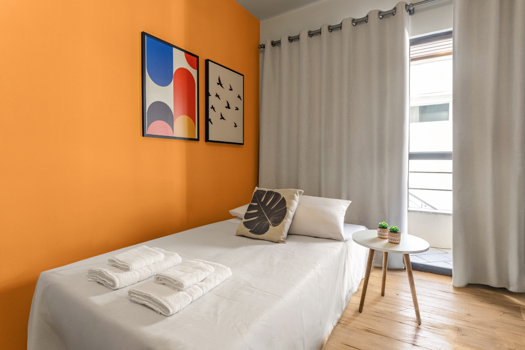 Quarto de solteiro do Apartamento 102 com parede laranja