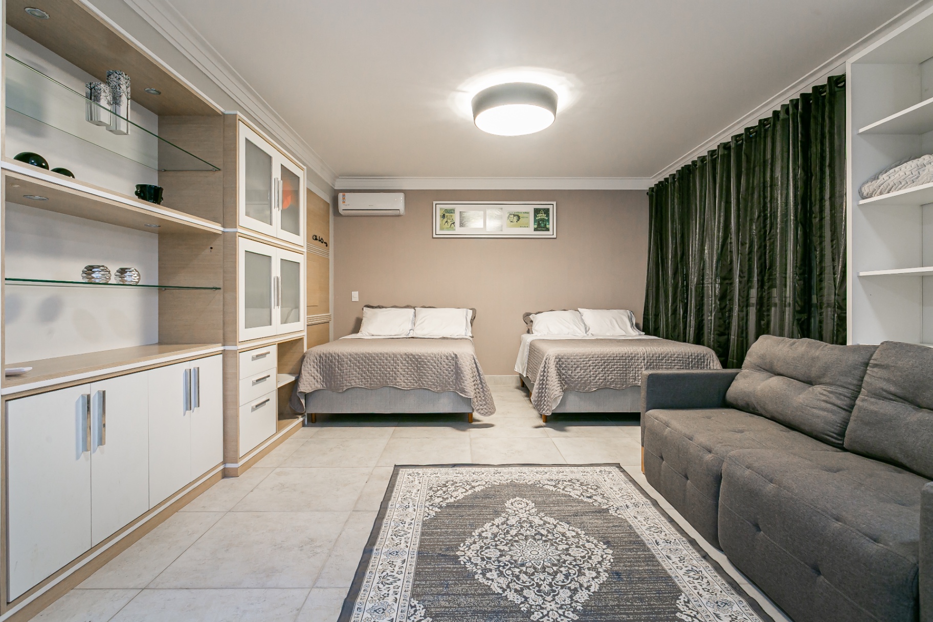 Suíte ampla da Casa Nevi com duas camas, sofá e armários embutidos