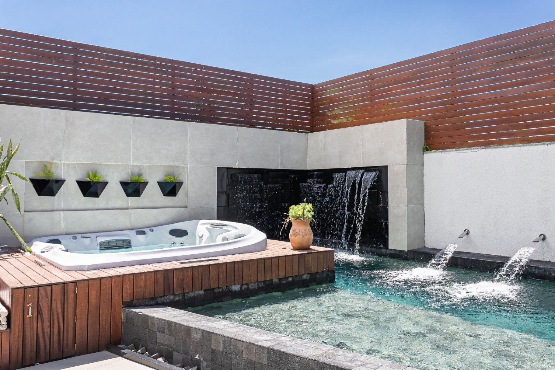 Área externa da Casa Nevi com piscina, jacuzzi e cascata de pedra