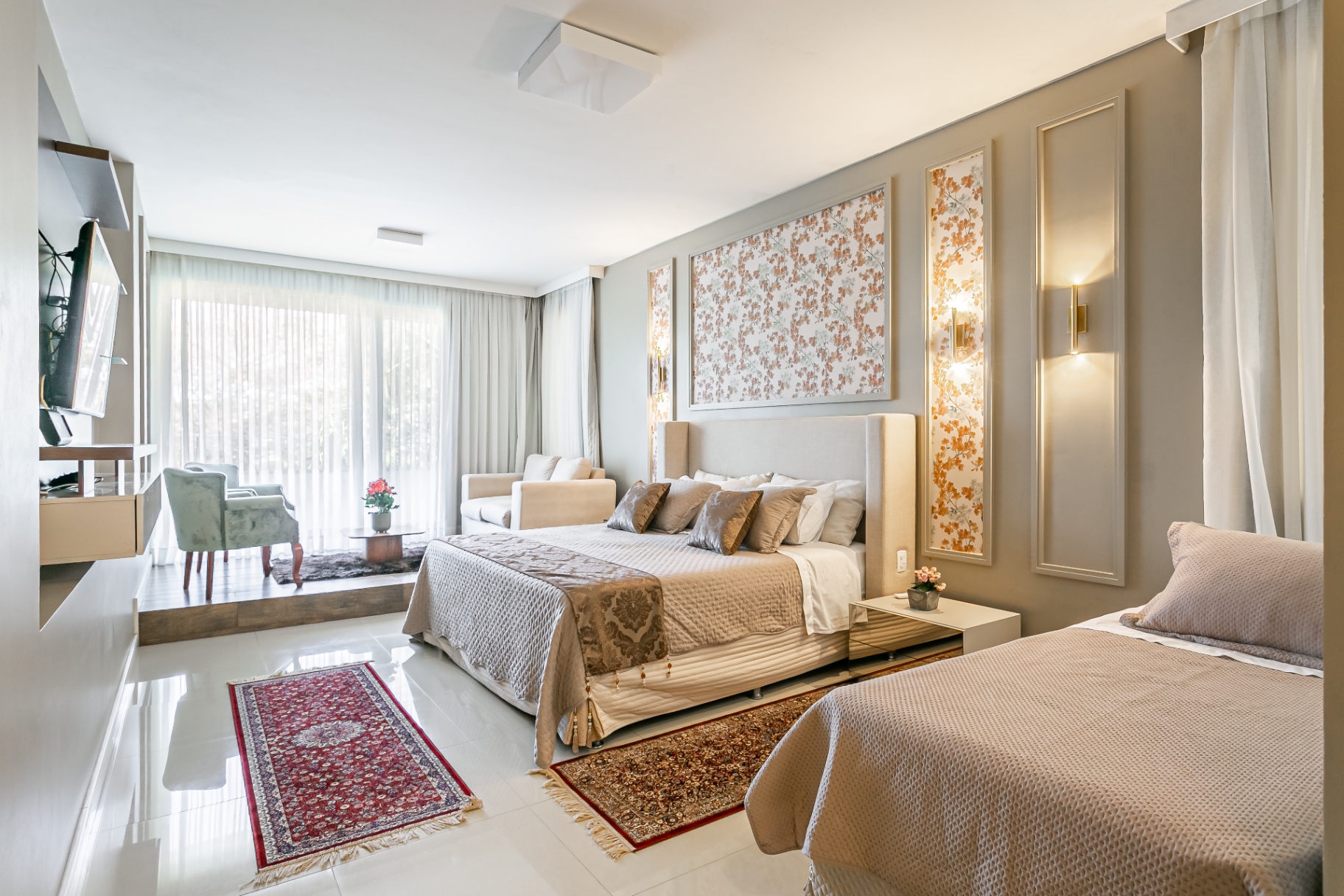 Suíte ampla da Casa Noah com cama de casal, cama de solteiro e área de estar