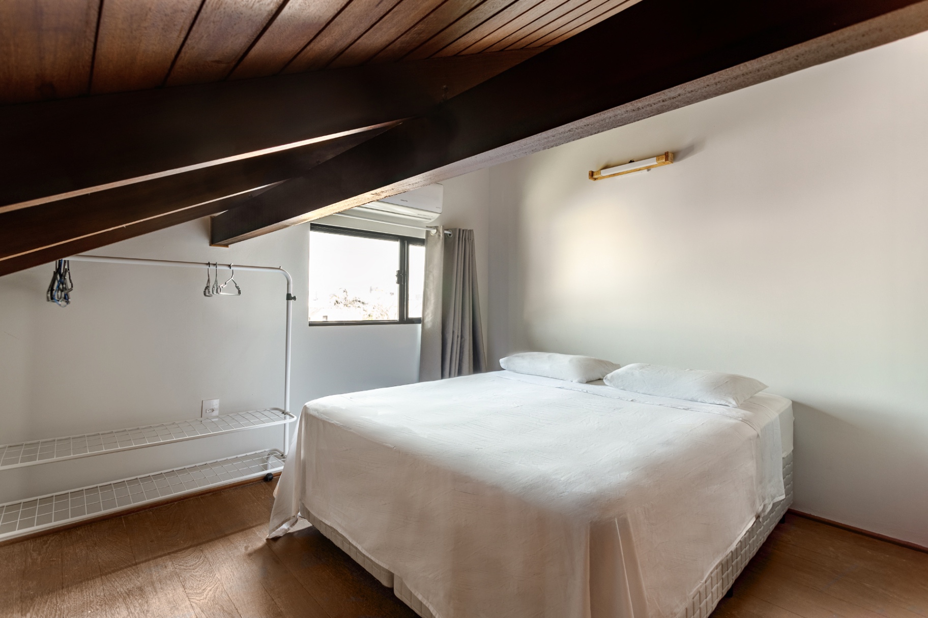Quarto do mezanino do Loft 203 com teto inclinado de madeira