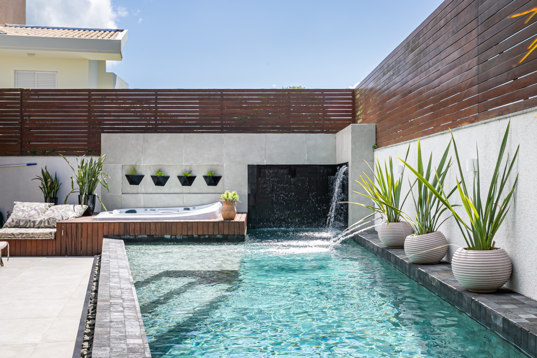 Vista panorâmica da piscina da Casa Nevi com bicas ornamentais e deck de descanso