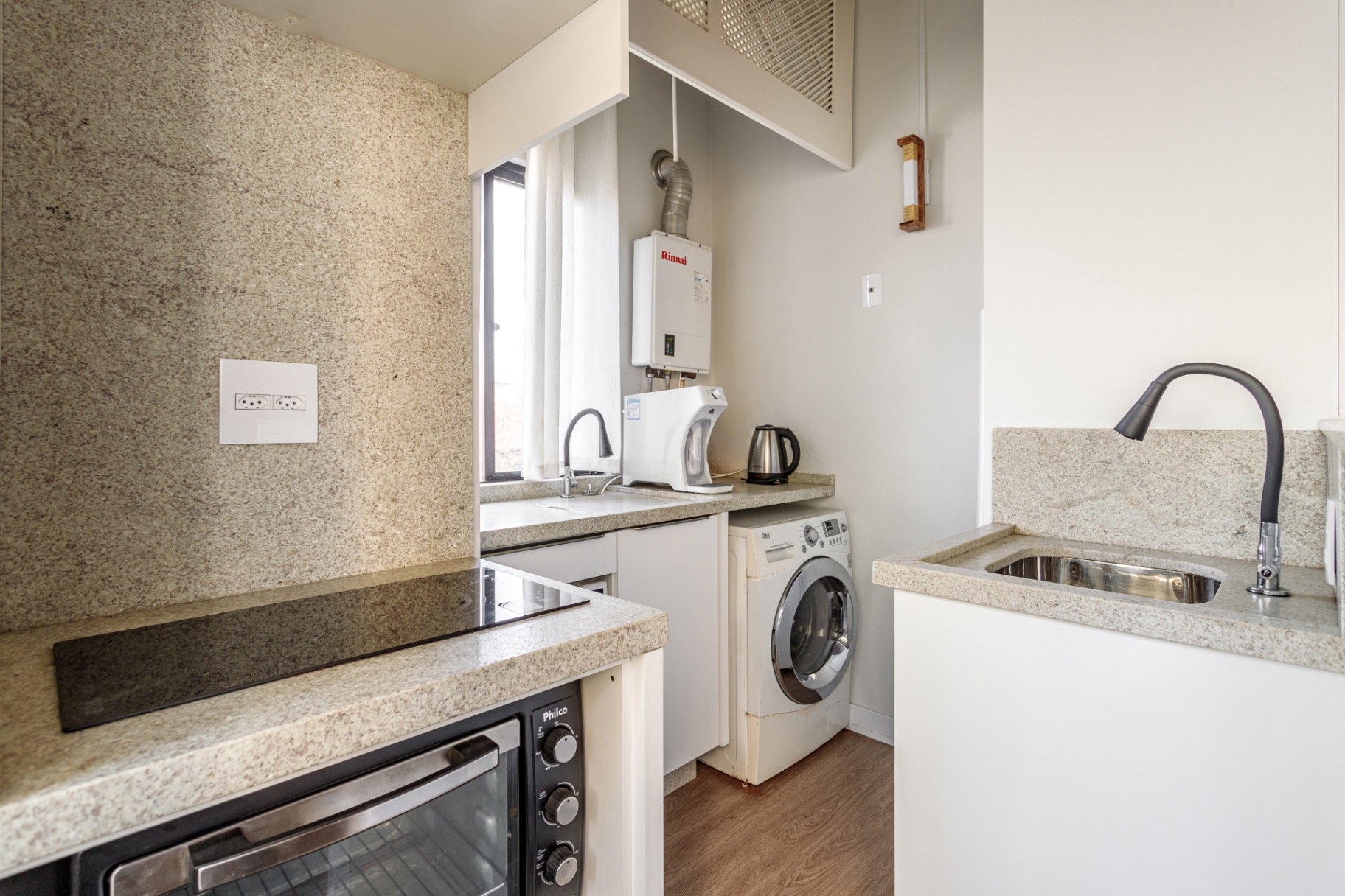Cozinha compacta do Loft 203 com cooktop e máquina de lavar