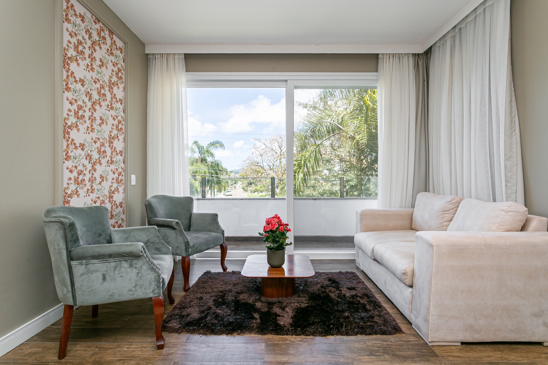 Sala de estar da Casa Noah com poltronas, mesa de centro e acesso à varanda