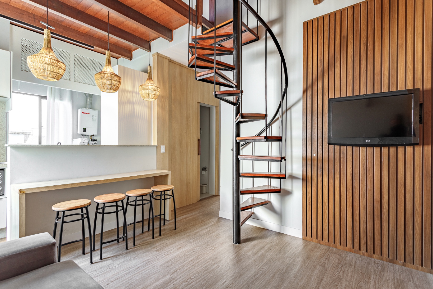 Sala do Loft 203 com painel de ripas de madeira e TV