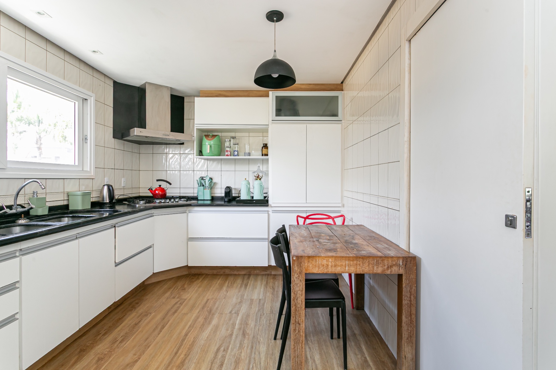 Área de jantar da cozinha da Casa Noah com mesa de madeira e luminária pendente