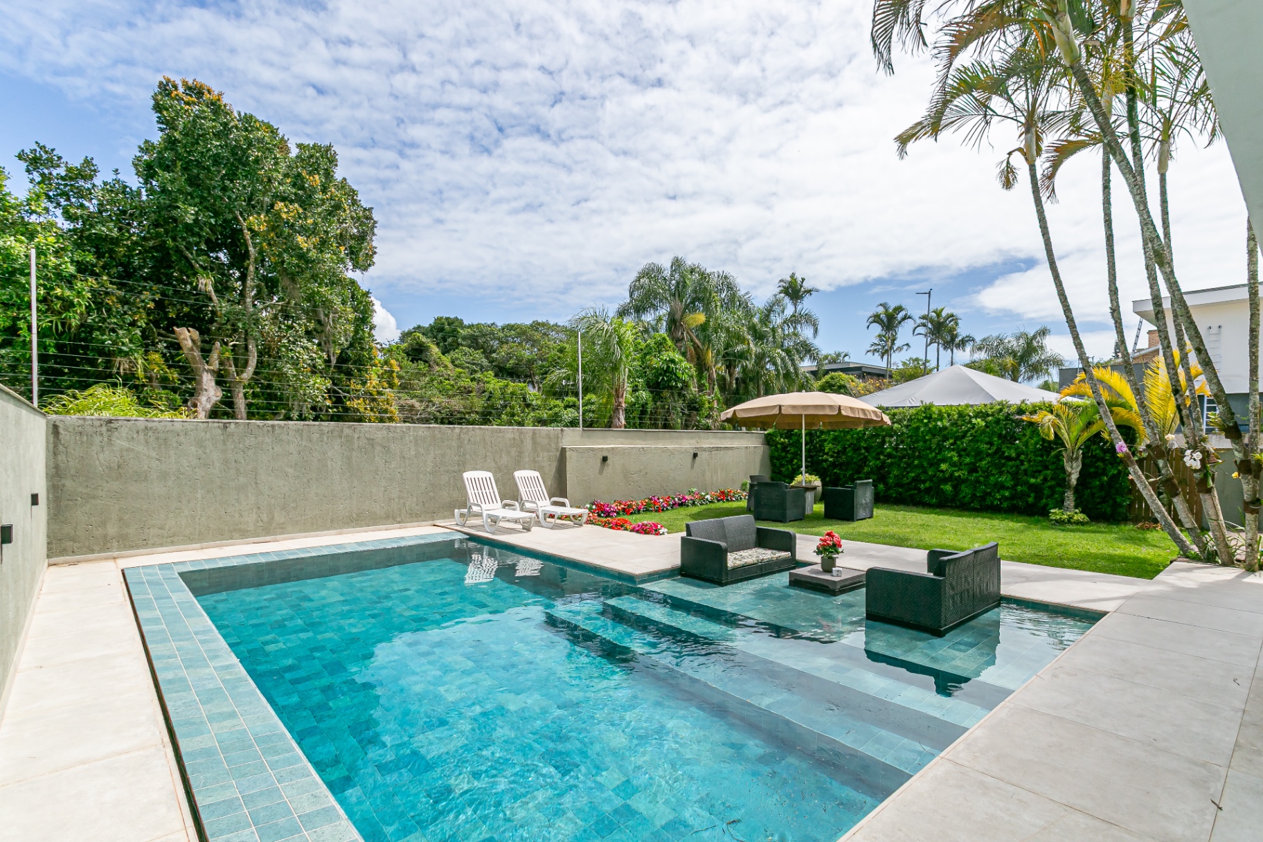 Área externa da Casa Noah com piscina, espreguiçadeiras e jardim